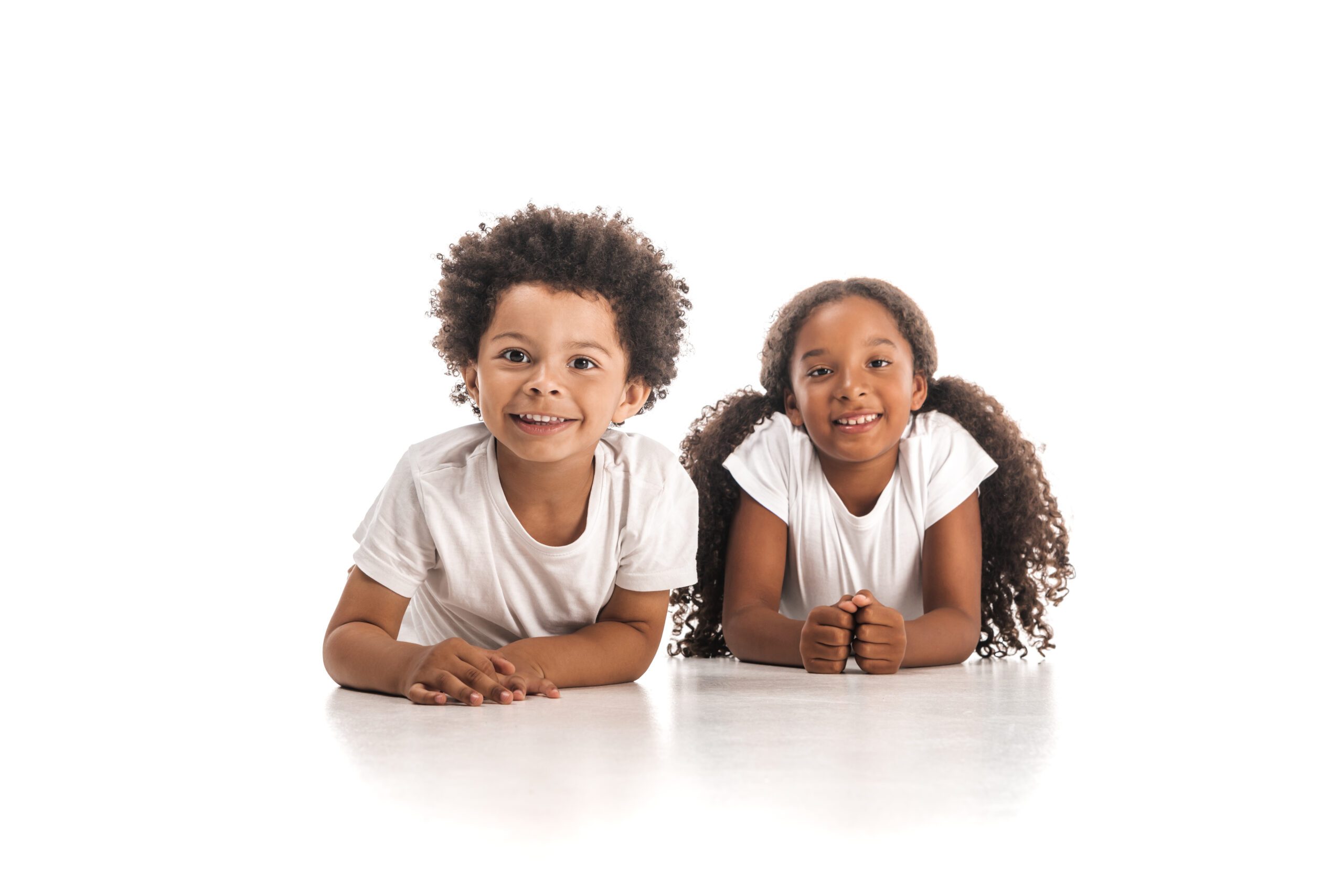 happy african american brother and sister smiling at camera while lying on white background